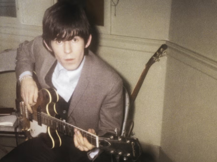 Young Keith Richards practicing guitar in a small room