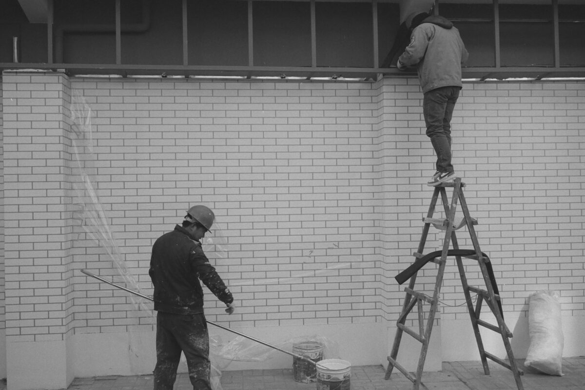 Worker standing on a ladder against a brick wall symbolizing business growth built on borrowed access.